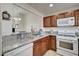 Traditional kitchen featuring granite counters, wooden cabinets, stainless sink, and white appliances with open serving area at 5000 Red Rock St # 248, Las Vegas, NV 89118