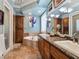 Bright bathroom featuring double sinks, a soaking tub, a cabinet, and earth tone tile flooring at 5416 Alabaster Ct, Las Vegas, NV 89149