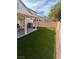 Inviting backyard featuring a covered patio, artificial turf lawn, and a well-maintained perimeter fence at 6022 Highland Gardens Dr, North Las Vegas, NV 89031