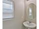 Compact powder room with a sleek pedestal sink and a large oval mirror at 6207 Hamilton Ave, Las Vegas, NV 89122