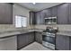 Corner view of a kitchen with stainless steel appliances, granite countertops and gray cabinets at 6207 Hamilton Ave, Las Vegas, NV 89122