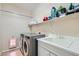 A practical laundry room featuring a washer, dryer, utility sink, and storage shelves at 6446 Button Quail St, North Las Vegas, NV 89084