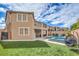 Two-story home featuring a balcony overlooking a green backyard with pool and lounge area at 689 Sea Star St, Henderson, NV 89002