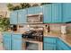 Bright kitchen featuring turquoise cabinets, granite countertops and stainless steel appliances at 724 Smokey Mountain Ave, Henderson, NV 89012