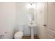 Small powder room featuring a pedestal sink, oval mirror, toilet, and modern fixtures at 7316 Childers Ave, Las Vegas, NV 89178