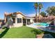 Private backyard with a pool, artificial grass, patio seating, and blooming landscaping at 8150 Beaverbrook Way, Las Vegas, NV 89123