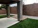 A covered backyard patio with an artificial turf area, stone pavers, and a brick wall at 8745 Dodds Canyon St, Las Vegas, NV 89131