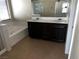 Bright bathroom with dual sinks, dark wood cabinets, separate tub and shower, and neutral tile floors at 8745 Dodds Canyon St, Las Vegas, NV 89131