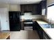 Modern kitchen features black appliances, dark wood cabinets and tan countertops and tiled floors at 8745 Dodds Canyon St, Las Vegas, NV 89131