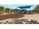 Bright, covered playground with swings, slides, and play equipment surrounded by safety surfacing at 900 Cantura Mills Rd, Henderson, NV 89052
