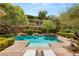 Beautiful backyard pool featuring a rock wall, spa, and lush landscaping at 900 Cantura Mills Rd, Henderson, NV 89052
