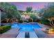 Inviting backyard pool and spa with rock wall feature, lush landscaping, and lounge chairs at 900 Cantura Mills Rd, Henderson, NV 89052