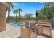 Outdoor kitchen area with built-in stainless grill, fridge, sink and a beautiful swimming pool at 9017 Cotton Rose Way, Las Vegas, NV 89134