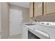 Well-lit laundry room with modern washer and dryer, ample cabinet space, and a tiled floor at 9017 Cotton Rose Way, Las Vegas, NV 89134