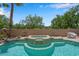 Backyard pool with integrated jacuzzi, stone trim and a privacy wall surrounded by mature trees and desert landscaping at 9017 Cotton Rose Way, Las Vegas, NV 89134
