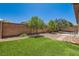 Well-maintained backyard with lush artificial grass, mature trees, and a paved seating area at 10121 Iron Wood Peak Ave, Las Vegas, NV 89166