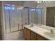Bathroom featuring double sinks, large mirror, and shower with sliding glass doors at 10357 Bent Willow Ave, Las Vegas, NV 89129
