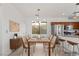 Bright dining room featuring a long wooden table, modern lighting, and adjacent kitchen at 10650 Little Horse Creek Ave, Las Vegas, NV 89129