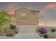 Inviting home featuring a two-car garage and well-maintained landscaping at sunset at 10650 Little Horse Creek Ave, Las Vegas, NV 89129