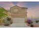 Inviting home featuring a two-car garage and well-maintained landscaping during twilight at 10650 Little Horse Creek Ave, Las Vegas, NV 89129