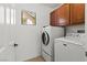 Bright laundry room featuring modern washer and dryer with overhead cabinets at 10650 Little Horse Creek Ave, Las Vegas, NV 89129