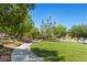 Neighborhood park featuring green grass, sidewalks, covered picnic benches, and lush trees at 10650 Little Horse Creek Ave, Las Vegas, NV 89129