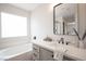 Well-lit bathroom with a large soaking tub, a gray vanity with white countertop, and modern fixtures at 10712 Aire Dr, Las Vegas, NV 89144