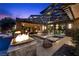 An outdoor living area featuring a pool, fire features and covered seating areas for luxurious outdoor entertainment at 11 Golden Sunray Ln, Las Vegas, NV 89135