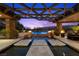 Stunning outdoor pool area featuring fire pits, stone accents, and a covered lounge space, perfect for evening relaxation at 11 Golden Sunray Ln, Las Vegas, NV 89135