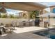 Covered outdoor kitchen with stainless steel appliances, a patterned backsplash, and a nearby pool at 11830 Kingsbarns Ct, Las Vegas, NV 89141