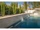 Captivating view of a modern pool with a sleek waterfall feature and lush landscaping, creating a serene oasis at 11830 Kingsbarns Ct, Las Vegas, NV 89141