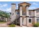 Two-story condo featuring stairs, red gravel landscaping, and tan stucco with dark trim at 1575 W Warm Springs Rd # 2822, Henderson, NV 89014