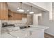 Modern kitchen featuring white marbled countertops, stainless steel appliances, and wood-tone cabinets, complemented by stylish pendant lights at 2117 Desert Peak Rd, Las Vegas, NV 89134