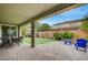 Covered back patio featuring custom brickwork, a cozy seating area, and a well-maintained lawn with playset at 2433 Amatrice St, Henderson, NV 89044