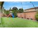 Spacious backyard with artificial grass, a playhouse, and landscaped borders, perfect for outdoor activities at 2433 Amatrice St, Henderson, NV 89044