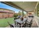 View of the covered patio with an outdoor dining set overlooking the beautifully landscaped backyard at 2433 Amatrice St, Henderson, NV 89044