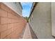 Narrow side yard with a brick walkway and gravel landscaping, providing access between the front and back of the house at 2433 Amatrice St, Henderson, NV 89044