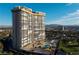 Angle view of high-rise exterior featuring a pool, tennis court, sunbathing chairs, and city views at 3111 Bel Air Dr # 20H, Las Vegas, NV 89109