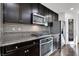 Close up of modern kitchen with granite countertops, stainless steel appliances, and dark wood cabinets at 382 Gracious Way, Henderson, NV 89011