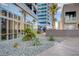 Modern building exterior featuring a stone garden, lush tropical plants, and a reflective glass facade at 4525 Dean Martin Dr # 2901, Las Vegas, NV 89103