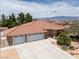 Expansive front view of the home with a three car garage, mature trees, and desert landscaping at 4650 Stoneham St, Pahrump, NV 89061
