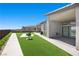 Backyard with a modern outdoor fireplace, lush green lawn and tiled patio at 5166 Stone View Dr, Las Vegas, NV 89135