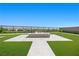 Backyard with a modern fire pit surrounded by green grass and lush landscaping at 5166 Stone View Dr, Las Vegas, NV 89135