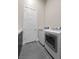 Bright laundry room featuring gray tile, front loading washer and dryer, and a white door at 5166 Stone View Dr, Las Vegas, NV 89135