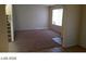Living room with tan carpet, white walls, arched doorway, staircase and window with blinds at 5308 La Quinta Hills St, North Las Vegas, NV 89081