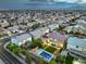 Expansive aerial view of a neighborhood featuring homes with backyard pools against a backdrop of mountains and city lights at 5480 Oatfield St, North Las Vegas, NV 89081