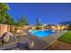 Lush backyard featuring a pool, daybeds, a basketball hoop, and desert landscaping with subtle lighting at 5480 Oatfield St, North Las Vegas, NV 89081