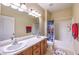 Well-lit bathroom featuring double sinks, vanity, a large mirror, and bathtub with shower at 5480 Oatfield St, North Las Vegas, NV 89081