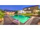 Backyard swimming pool with a basketball hoop at twilight surrounded by concrete patio and green lawn at 5480 Oatfield St, North Las Vegas, NV 89081