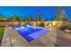 Backyard pool with basketball hoop, lounge chairs and a hammock by a block wall at twilight at 5480 Oatfield St, North Las Vegas, NV 89081